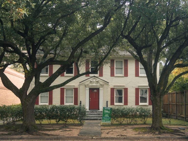 Classic colonial house with red shutters and trees in Houston, Texas, available for lease.