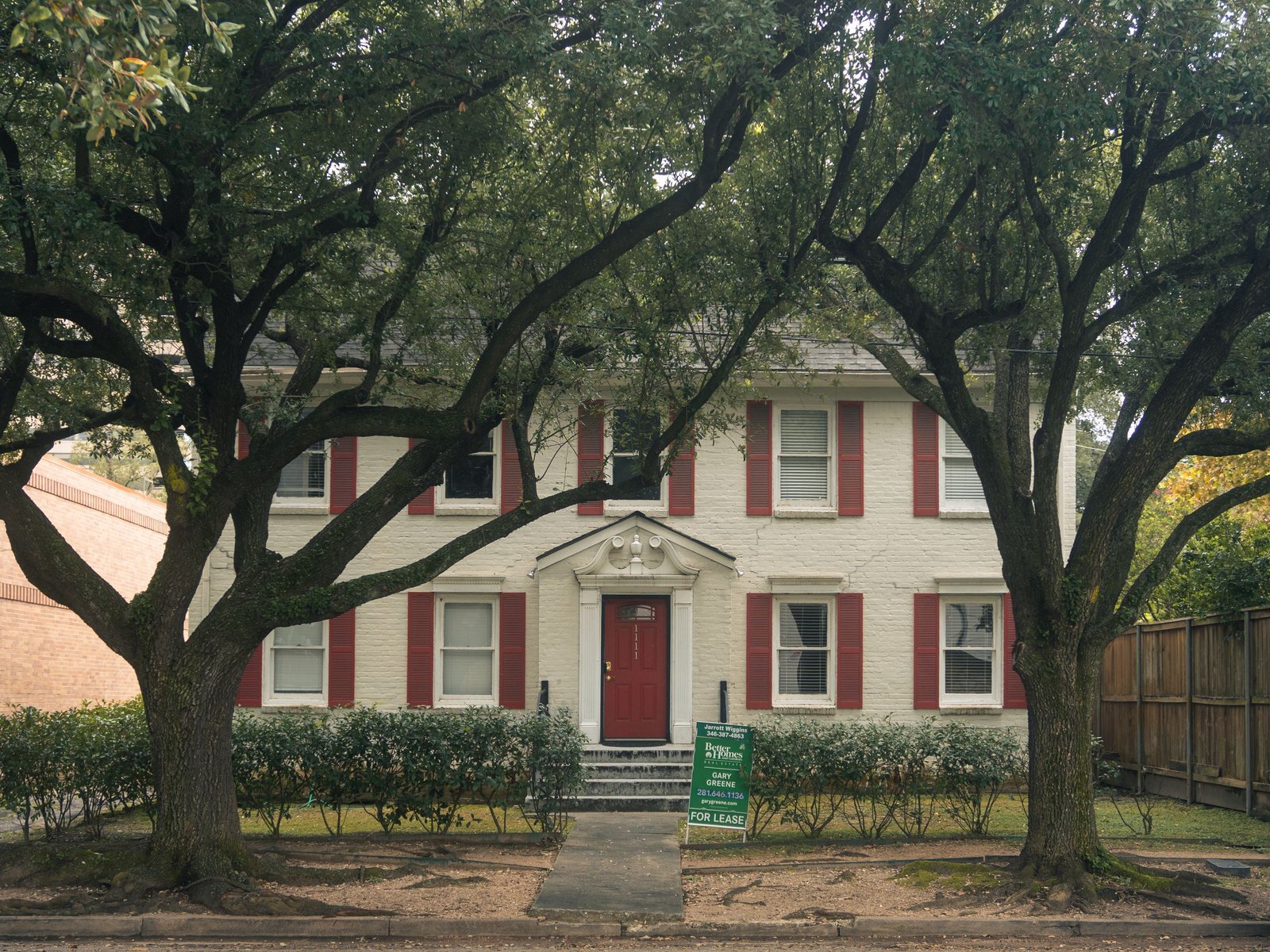 Classic colonial house with red shutters and trees in Houston, Texas, available for lease.